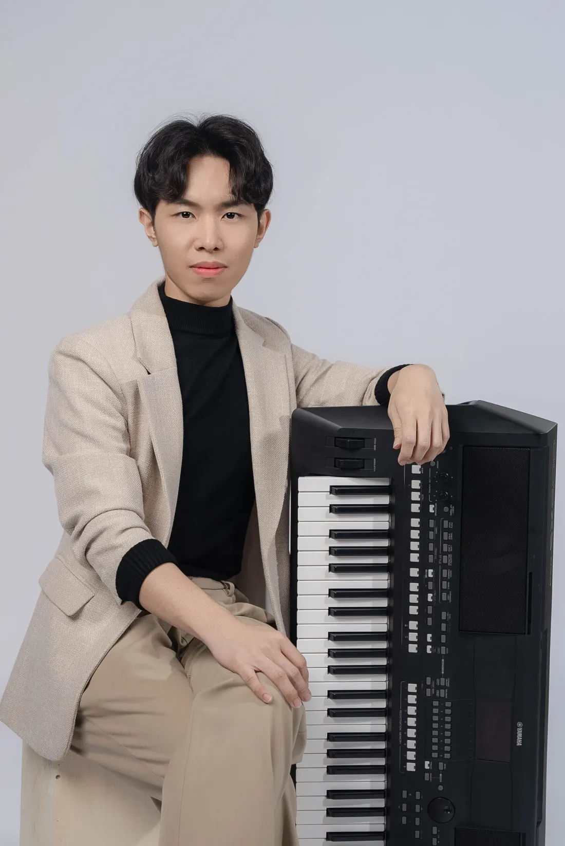 Derrick Ching, vocal and keyboard teacher and live band vocalist, seated beside his Yamaha keyboard