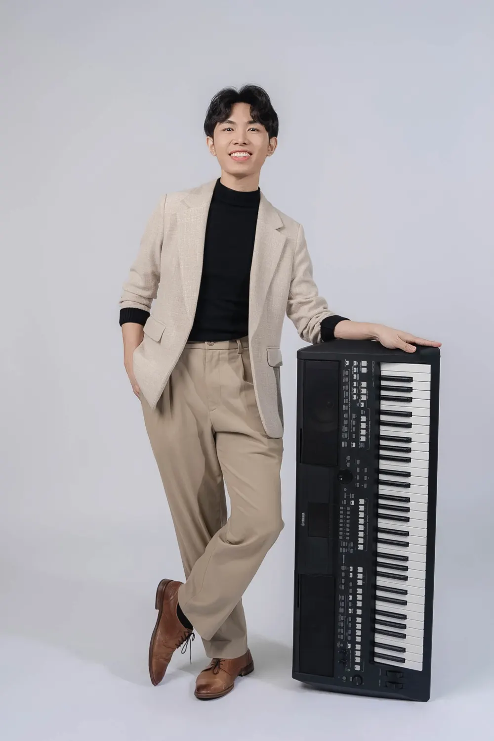 Derrick Ching, pop vocal and keyboard teacher, standing beside a Yamaha keyboard